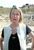 Photograph of A.E. Stallings standing with the ruins of ancient theatre behind her